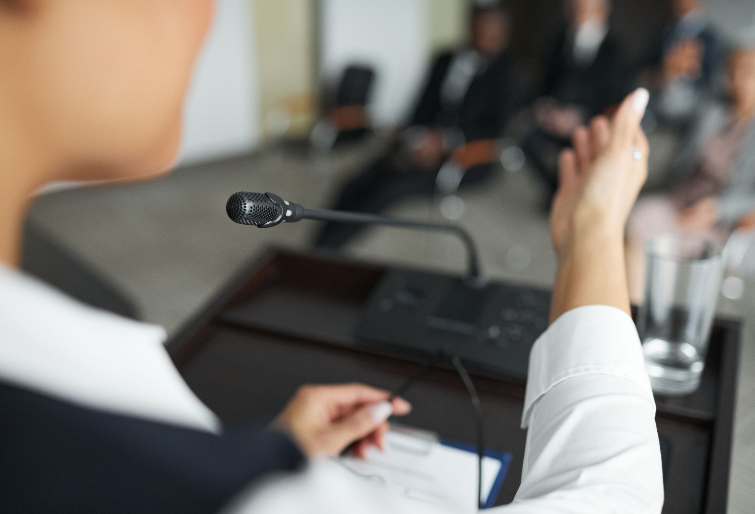 Hand adjusting a microphone at a hearing, expert witness testimony