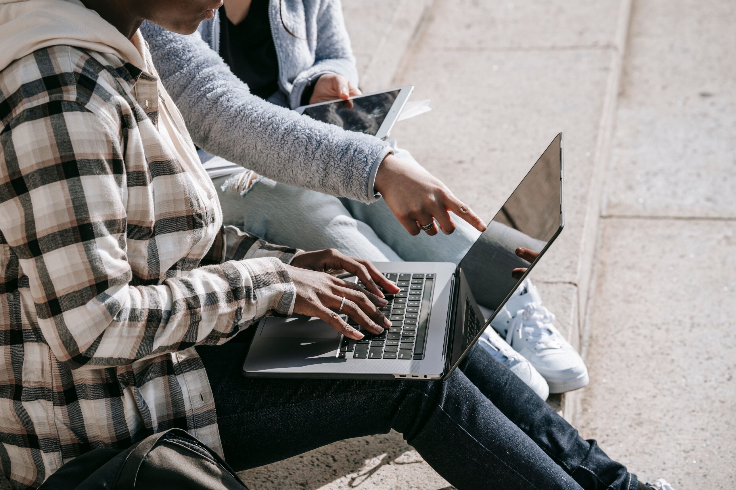 Students working on laptops outdoors, college application support
