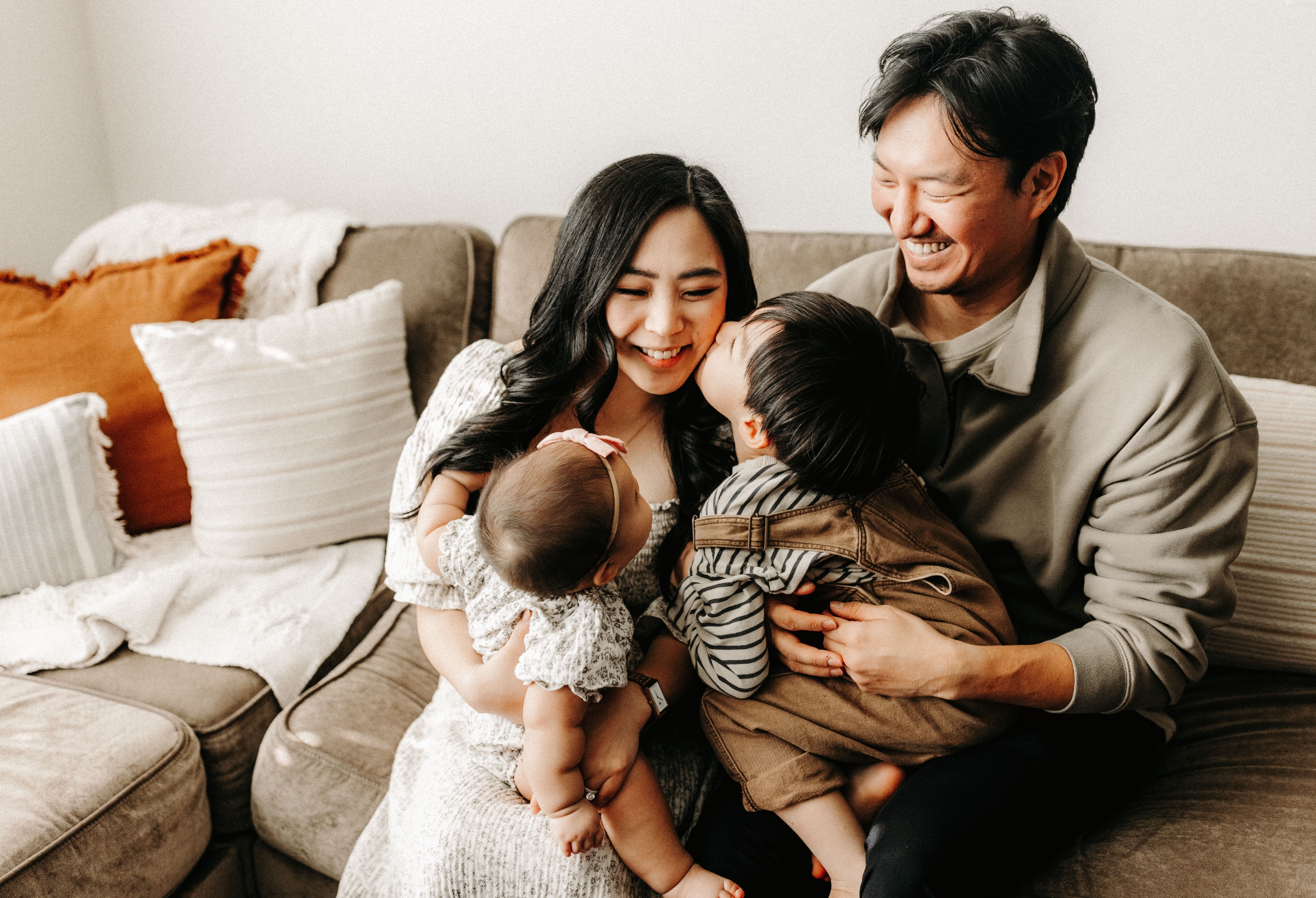 Family with two young children laughing together on a sofa, family therapy