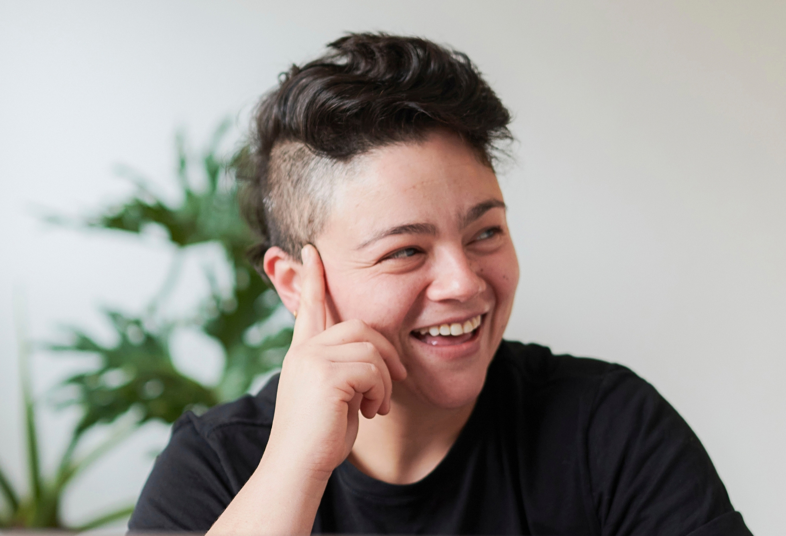 Smiling person resting their chin on their hand, gender-affirming therapy