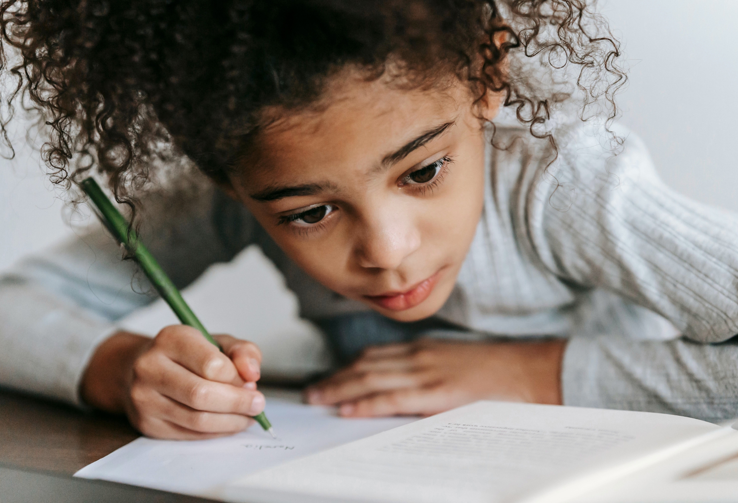 Child writing at a desk during an educational assessment