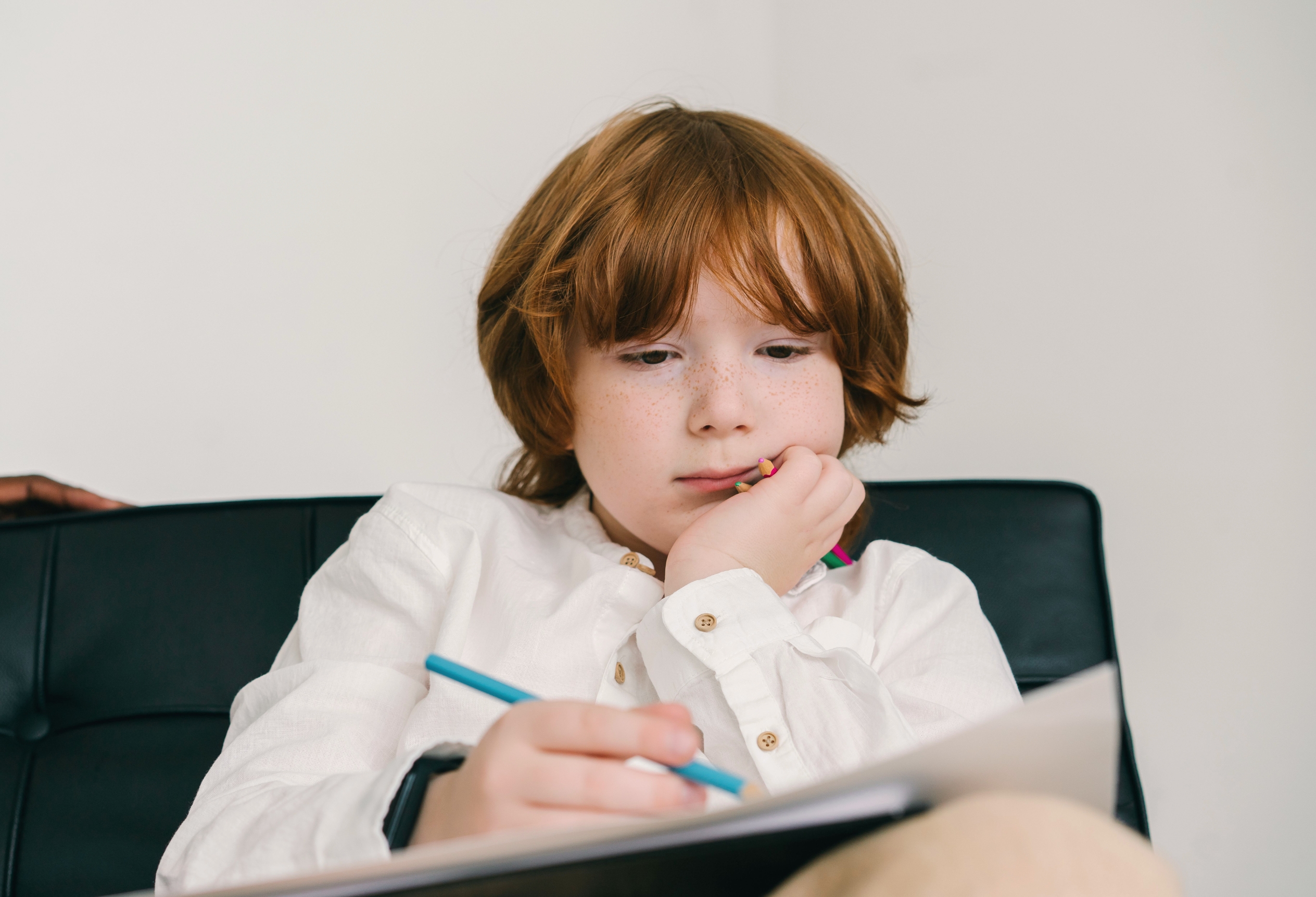 Young child smiling while writing at a desk