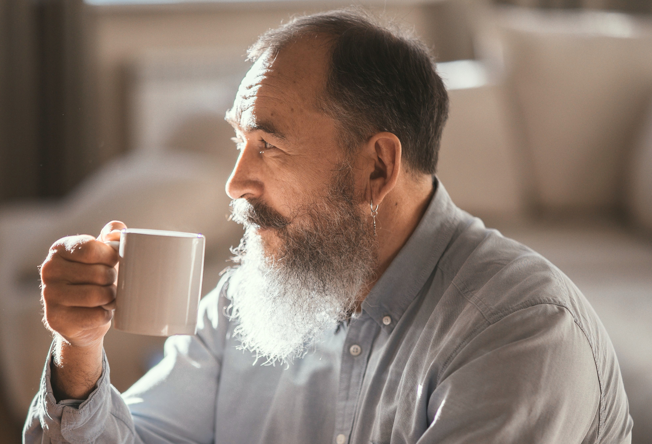 Older adult holding a mug and looking thoughtful, neuropsychological testing