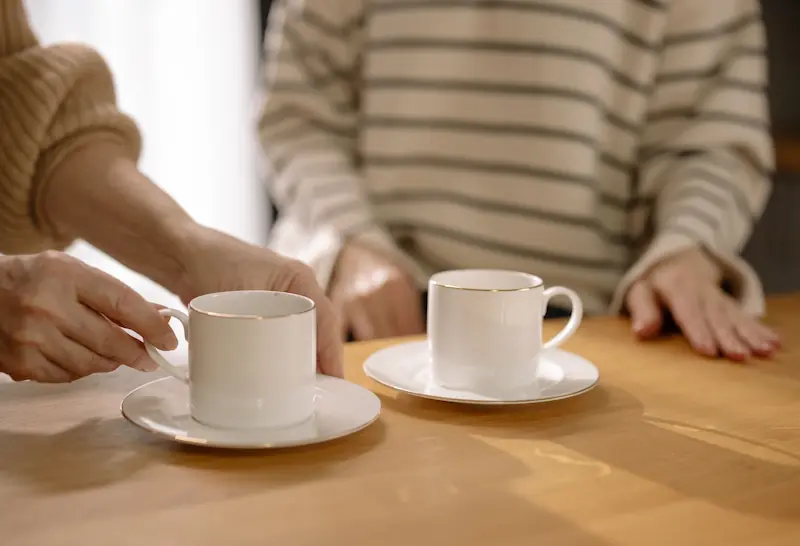 Two people talking over cups of coffee at a table